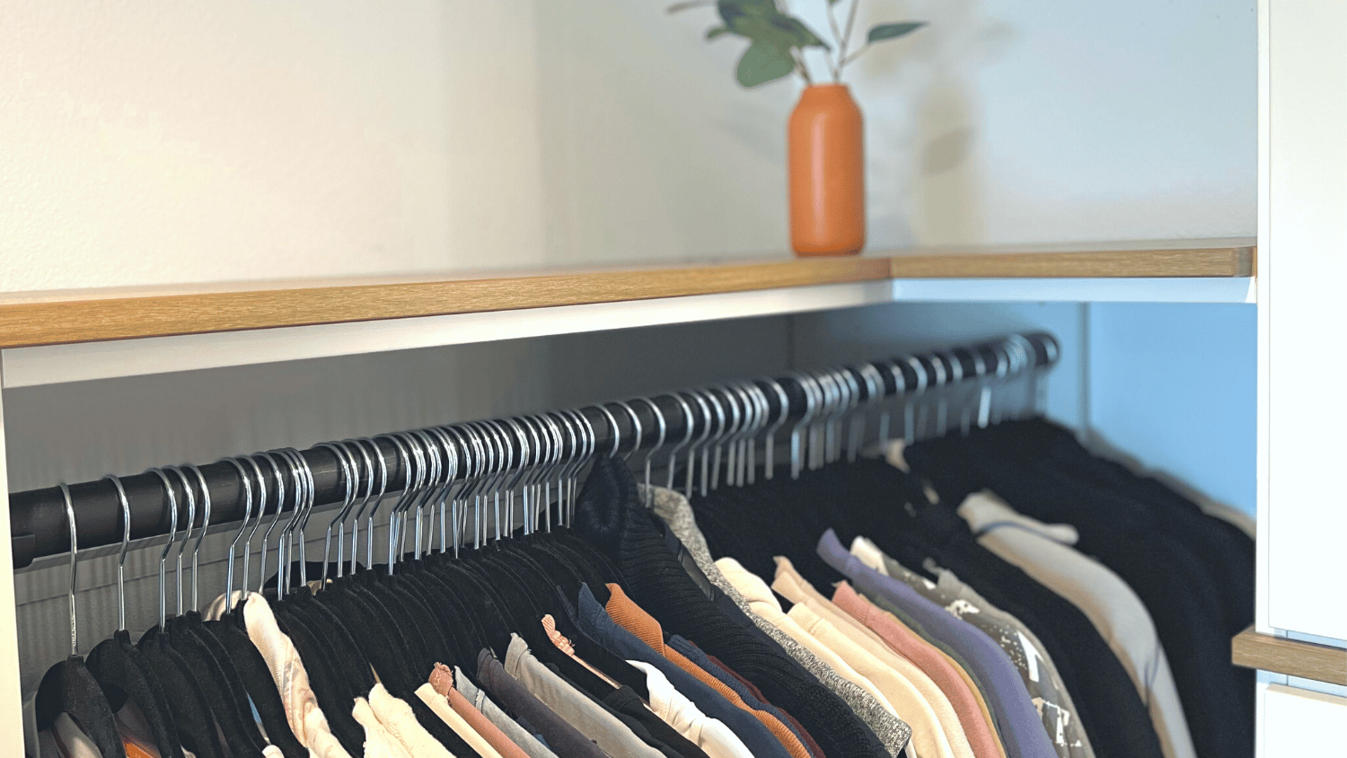 matching, black, slim velvet hangers hanging on a clothes rod in a closet