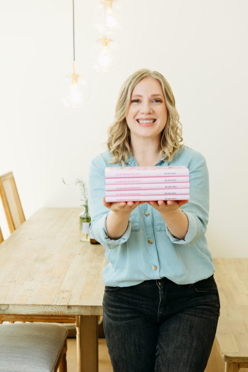 Melinda Grace with a stack of reclaim your space with grace books